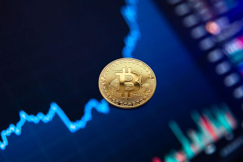 Bitcoin coin in front of a price chart as traders watch for a US government seized bitcoin sale