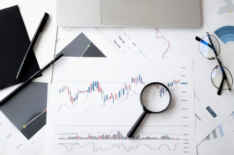 Financial charts under a magnifying glass illustrating the MOVE token collapse behind the Movement Labs Chapter 11 filing