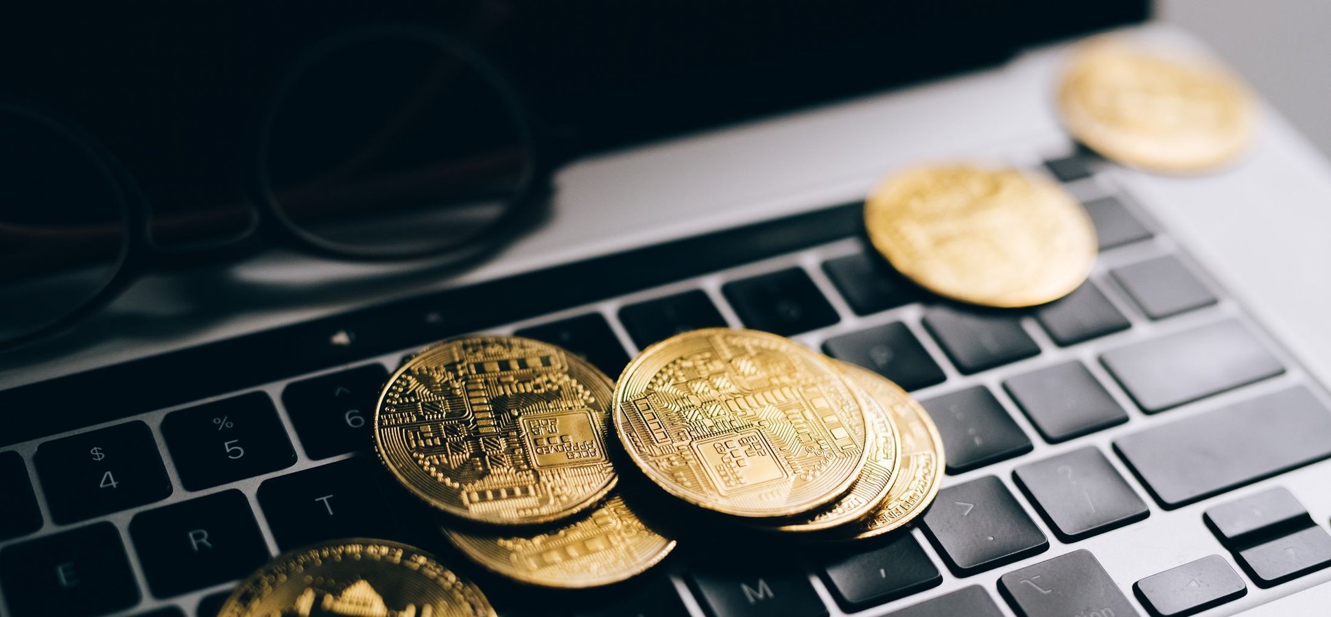 Ledger hardware wallet and gold crypto coins on a laptop keyboard illustrating the Ethereum app signing flaw